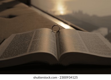 A closeup of a ring resting in between the pages of an open bible at sunrise in Mumbai