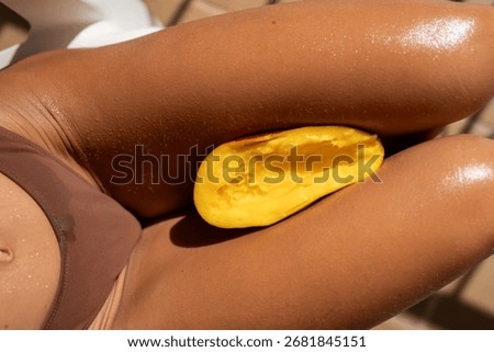 Closeup of ripe mango half placed on the thighs of a woman in br