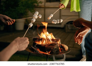 Closeup roasted marshmallows on skewers over open camping bonfire - Powered by Shutterstock