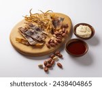 Close-up of roasted peanuts and a squid in pieces with chili pepper paste and mayonnaise on dish and wood board, South Korea
