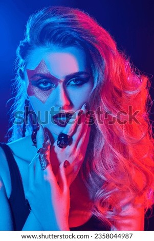Close-up of a rock star girl with bright glitter makeup and hair in glam rock style in colored stage lighting. Rock accessories. Rock and Pop music.