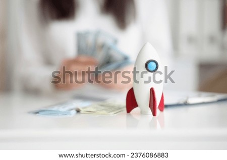 Close-up of rocket model on desk, rocketship symbol for startup, earn money on beneficial project. Success, growth, development, wealth, income concept
