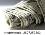 A close-up of a rolled up stack of one-dollar bills. Background with US dollars.