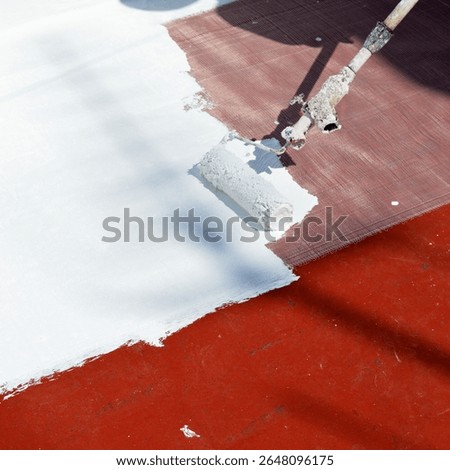 Closeup of a roller applying a layer of white rubber waterproofing paint with reinforcing fiberglass mesh to the building terrace. Waterproof and sealant paint. Heat treatment due to climate change.