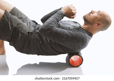 Close-up  Roller For Body Massage. Bald Guy Doing An Exercise  With Foam Roller On His Upper Back Against White Background.