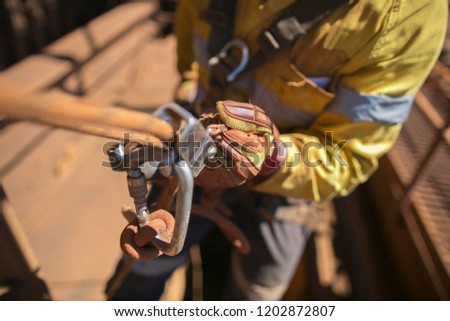 Closeup rope access industry worker hand wearing full body safety harness, using secondary safety backup device static twin ropes abseiling, descending from construction mine site, high rise building 