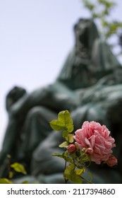A closeup of a rose in front of a blurred sculpture of Mary with Jesus - Shutterstock ID 2117394860