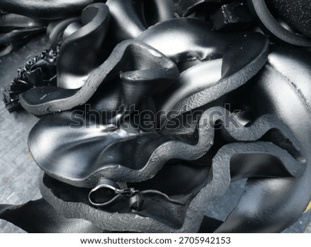Close-up of rough dark textured surface resembling cooled volcanic lava or charcoal rock. Abstract natural background with rugged, solidified molten structure and shiny black mineral details. High-res