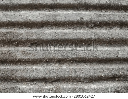 Close-up of rough grey concrete surface with horizontal grooved lines. Textured cement background with a gritty industrial look.