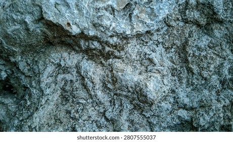 Close-up of a rough grey stone surface, natural rock cliff texture background.