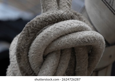 Close-up of the rough texture and pattern of a thick white rope tied in a knot.
