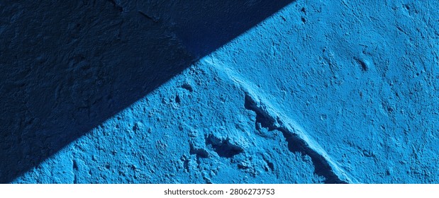 Close-up of a rough, textured blue surface divided by a sharp diagonal shadow, creating a minimalist abstract composition.