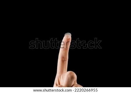 Close-up round acne patch on finger on black background. Acne patches for treatment of pimple and rosacea close-up. Facial rejuvenation cleansing cosmetology