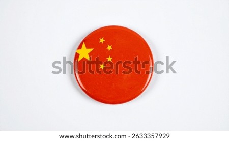 Closeup of a round Chinese flag button badge. Red background with a large yellow star and four smaller yellow stars. Oval shape, simple design.