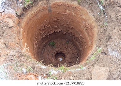 Close-up Of A Round Hole In The Ground. Digging A Well, Water Below, Mud, Earth, Water Supply