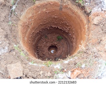 Close-up Of A Round Hole In The Ground. Digging A Well, Water Below, Mud, Earth, Water Supply