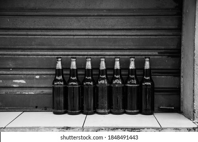A closeup of a row of empty ember bottles with blue paint on the neck