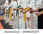 A close-up of a row of young athletes in white karate kimonos with clenched fists. A photo for a demonstration or karate competition. Energy and concentration concept.