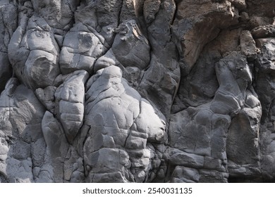 A close-up of rugged, textured rock formations showcasing unique shapes and patterns. The rough surface and shadows highlight natural details, creating a dramatic and raw display of geological beauty. - Powered by Shutterstock