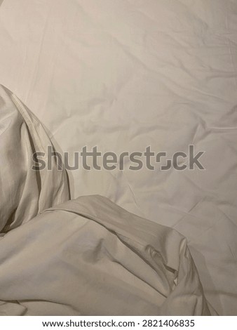 A close-up of rumpled white bed sheets and a duvet on a bed.