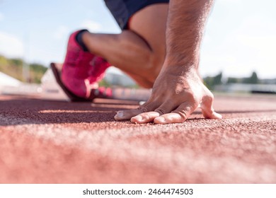 Close-up of runner ready to run on starting line. Shot of a male athlete waiting at the start line to begin a race - Powered by Shutterstock