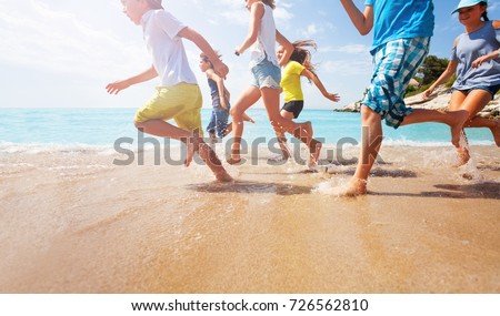 Close-up of running kids legs in shallow sea water