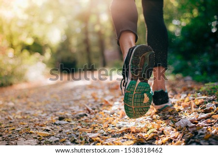Closeup of running shoe of the person running in the nature with beautiful sunlight.