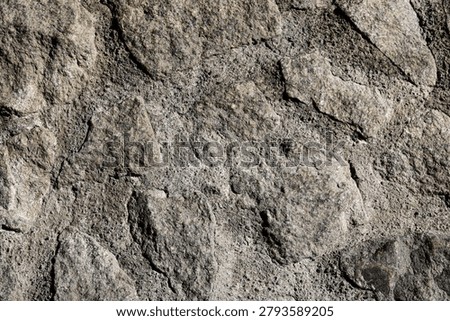 Close-up of a rustic cobblestone wall bonded with rough cement mortar for heavy masonry construction.
