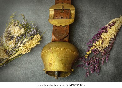 Close-up of a rustic old vintage cowbell arranged between dried flowers on black background