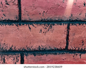 Close-up of a rustic red brick wall texture with distressed black mortar lines. This detailed background showcases weathered brickwork with a painted, textured surface and dark accents, creating an industrial, vintage, or grunge aesthetic. Perfect for architectural, construction, or abstract design backgrounds.