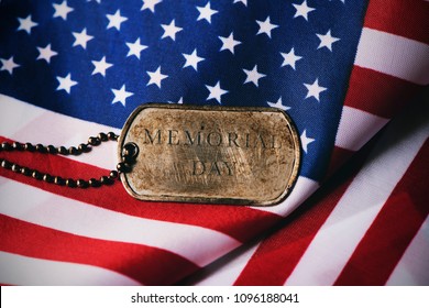 Closeup Of A Rusty Dog Tag With The Text Memorial Day Written In It On A Flag Of The United States