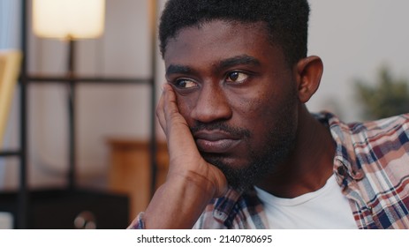 Close-up Sad Face Of African American Man Sitting At Home Looks Pensive Thinks Over Life Concerns Or Unrequited Love, Suffers From Unfair Situation. Problem, Break Up, Depressed Feeling Bad Annoyed