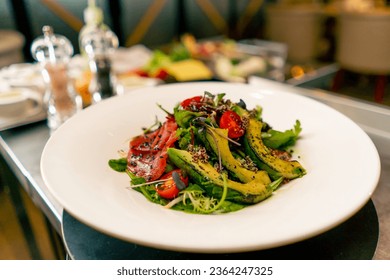 A close-up of a salad with avocado jamon and cherry tomatoes prepared in the professional kitchen of Italian restaurant - Powered by Shutterstock