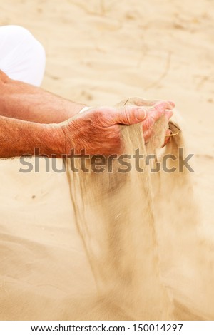 Close-up of sand falling from senior man's hand.