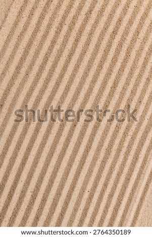 Close-up of sand with wavy, textured patterns creating a natural, soothing design. The ripples form a harmonious, repetitive pattern.