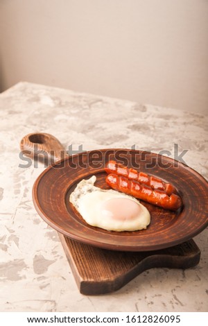 Close-up of sausages and fried eggs. Sausages on a plate and place for text. Breakfast fried eggs and bavarian sausages on a clay plate and copy space.