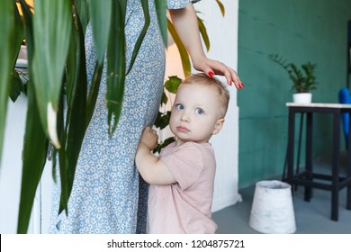 Closeup Scared And Shocked Little Baby Boy 2 Year Hid Behind His Mother, Beware Of Strangers Or Darkness. Human Emotion Face Expression. Child Seeking For Protection From Mom In Unrecognizable Place