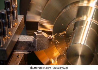 Closeup scene the lathe machine rough cutting the brass disk parts by lathe tools. The metalworking process by turning machine.