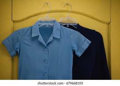 Close-up of school uniform and bag hanging on yellow door - Powered by Shutterstock