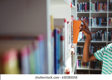 Close-up of schoolboy selecting book in library at school - Powered by Shutterstock