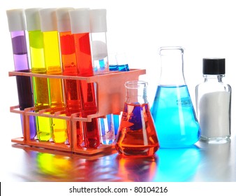 Closeup Of Scientific Labratory Equipment On Shiny Metal Surface. Test Tubes, Beakers And Vials Filled With Colorful Liquids On A White Background.