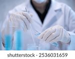 Close-up scientist pouring blue liquid into test tube beaker flask equipment pipette working laboratory experiment research chemical biology discovery healthcare and medicine accuracy solution