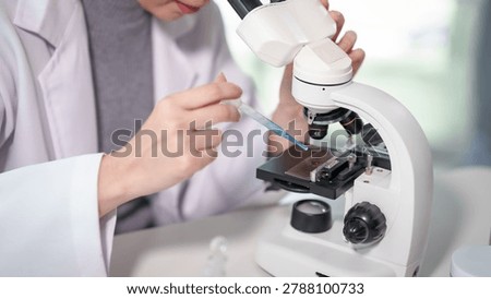 Close-up of a scientist using a pipette at a laboratory microscope to place a sample on a slide, clinical research and diagnostics concept.