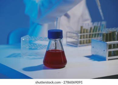 Close-up of a scientist using a precision pipette to drop orange liquid into a petri dish in a sterile laboratory environment.