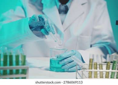 Close-up of a scientist using a precision pipette to drop orange liquid into a petri dish in a sterile laboratory environment.