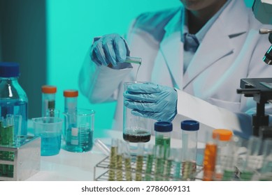 Close-up of a scientist using a precision pipette to drop orange liquid into a petri dish in a sterile laboratory environment.