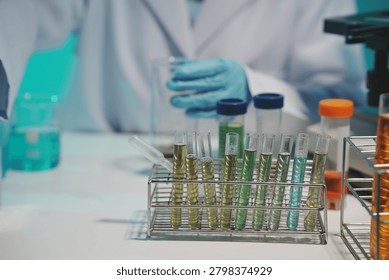 Close-up of a scientist using a precision pipette to drop orange liquid into a petri dish in a sterile laboratory environment.