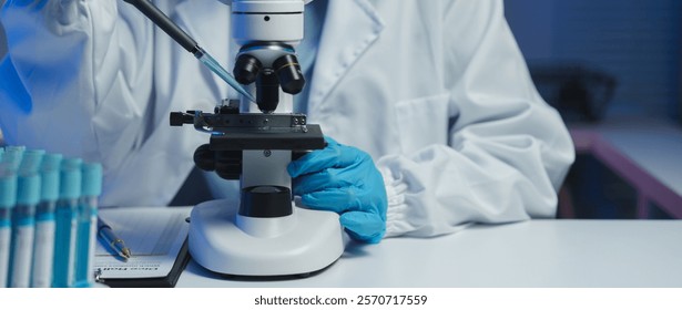 Close-up of scientist's hands using a microscope and pipette, conducting research and analysis in a modern laboratory setting with test tubes nearby - Powered by Shutterstock - Get 15% off with code: PIKWIZARD15