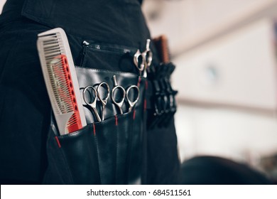 Closeup of scissors and combs in a salon holster pouch. Hairdressing tools inside a hairdresser waist pouch.