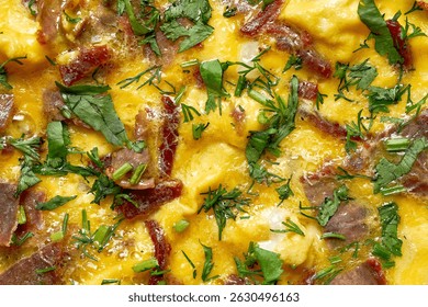 Close-up of scrambled eggs with dried meat and fresh herbs. The dish features soft, creamy scrambled eggs mixed with slices of cured or dried meat, possibly basturma or sausage.